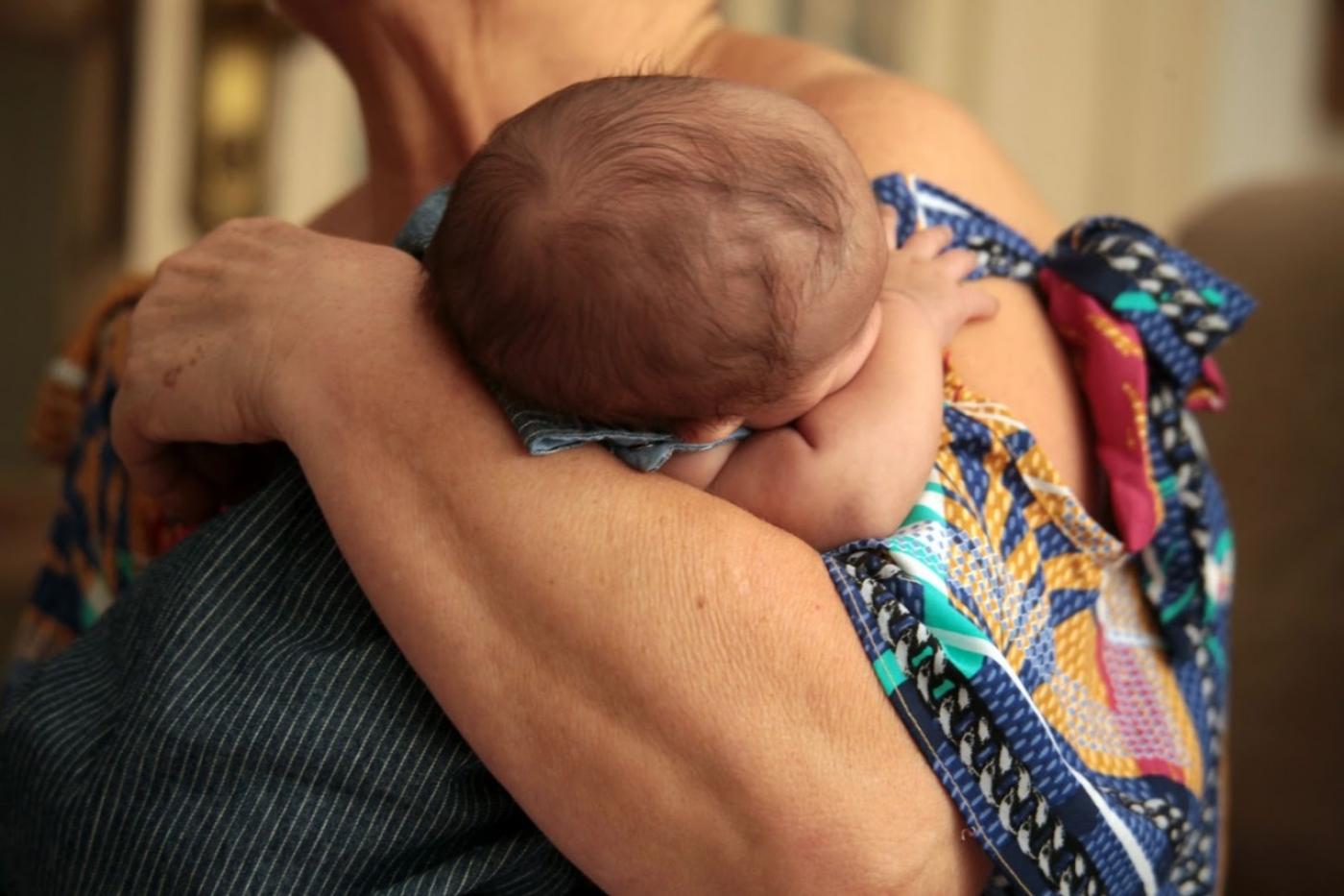 Bebê sendo abraçado e no colo de uma mulher. #paratodosverem