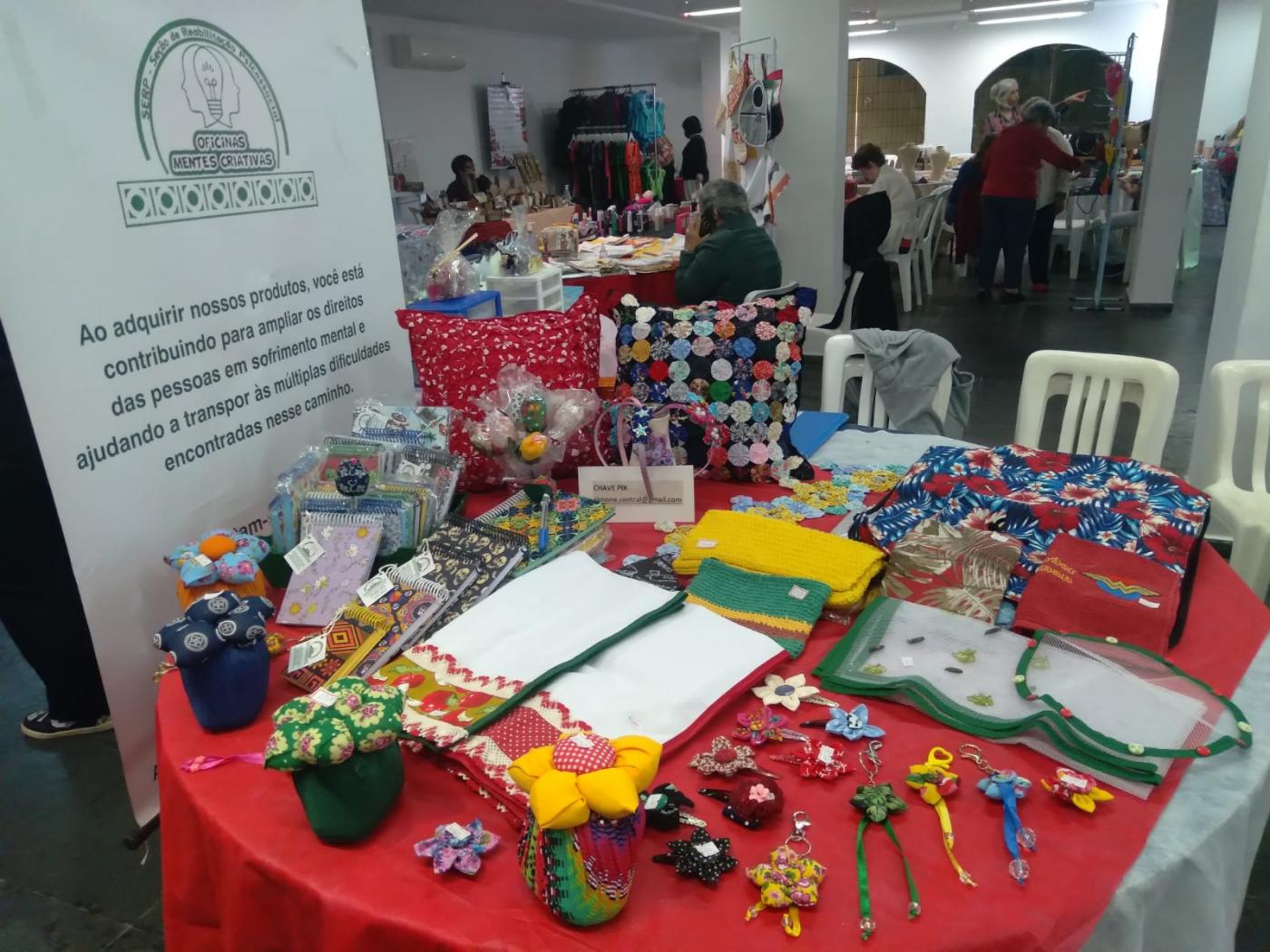 mesa com peças de artesanato como panos de prato, peças com fuxico e outras. #paratodosverem