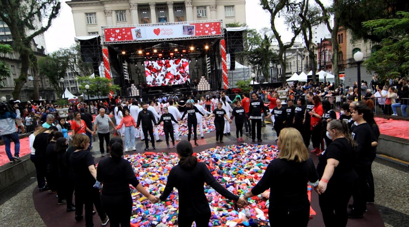 Participantes de mãos dadas em volta de corações espalhados pela praça. #pratodosverem