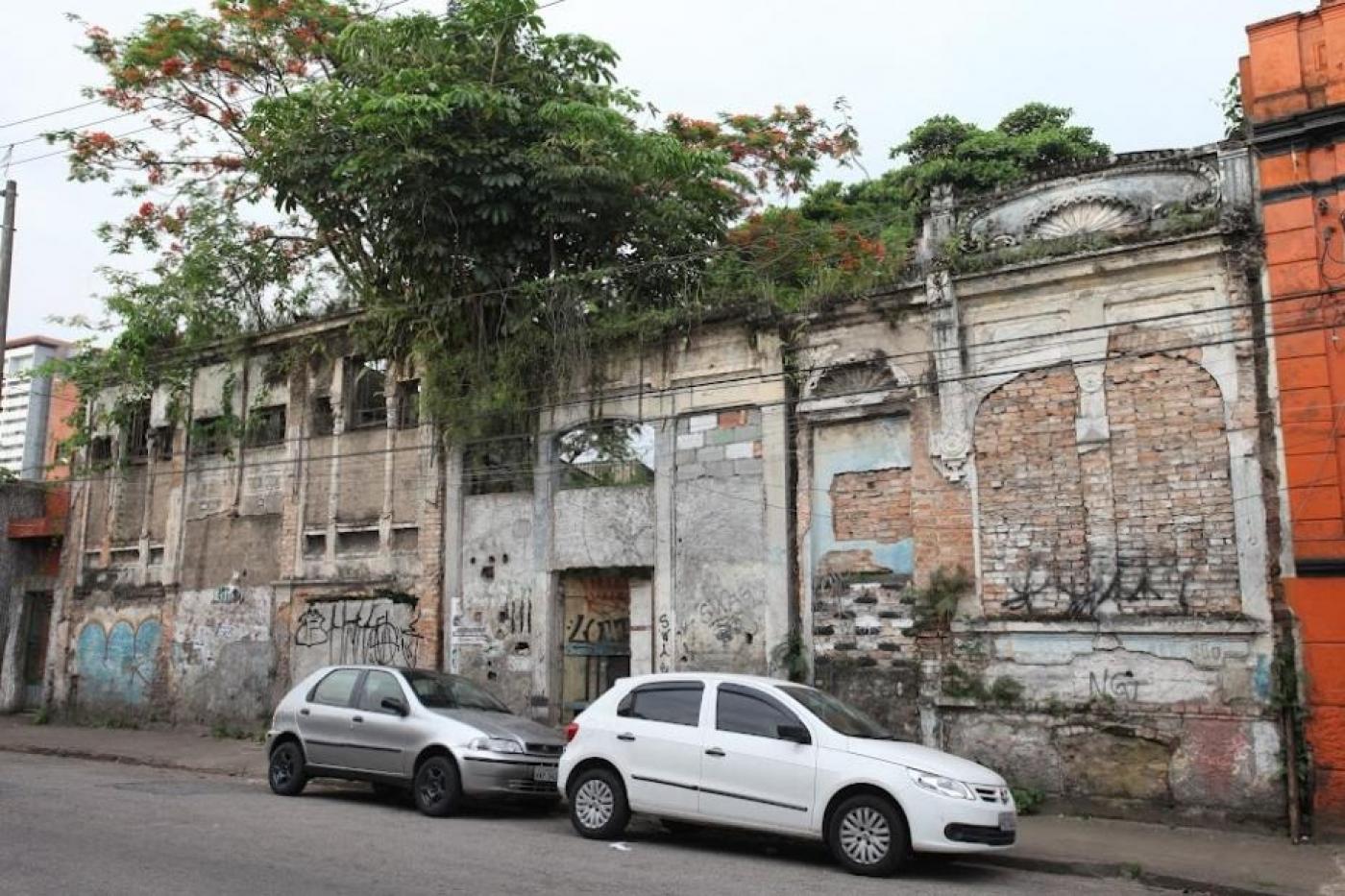 terreno em rua com muro na frente e dois carros parados na via. #paratodosverem