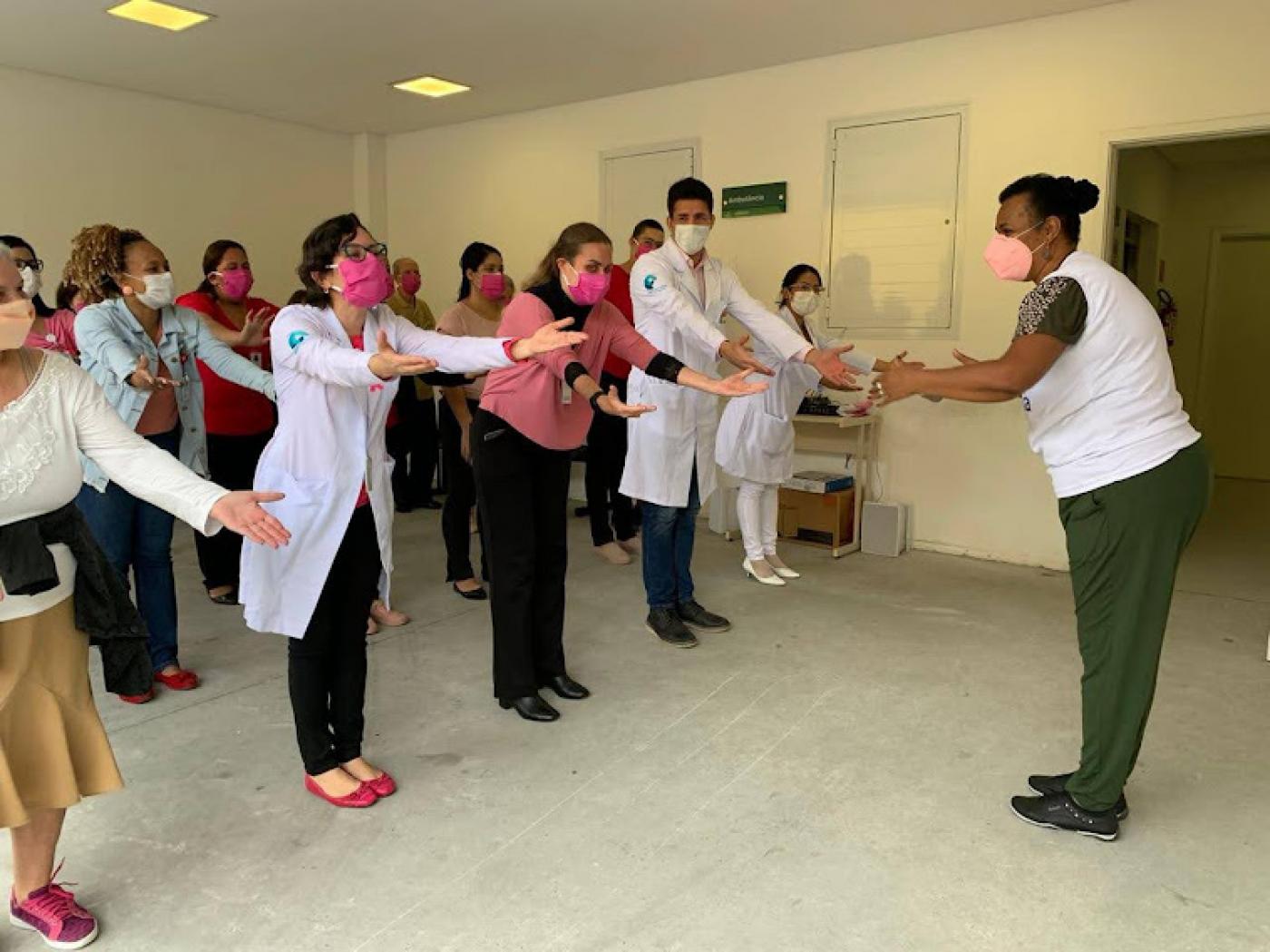 Pessoas na unidade realizam atividade estendendo a mão para frente #paratodosverem