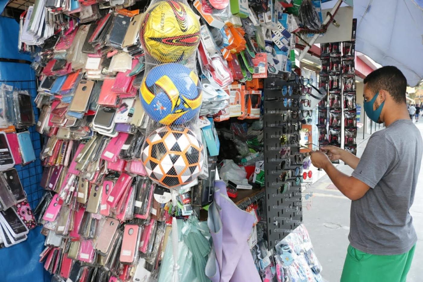 banca de comércio ambulante cheia de produtos pendurados, como óculos, capas de celular, brinquedos et