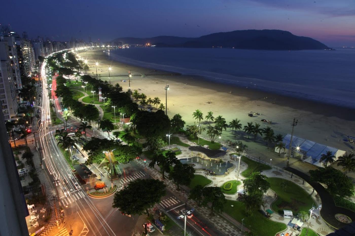 imagem aérea da praia, jardins, avenida e prédios a noite #paratodosverem