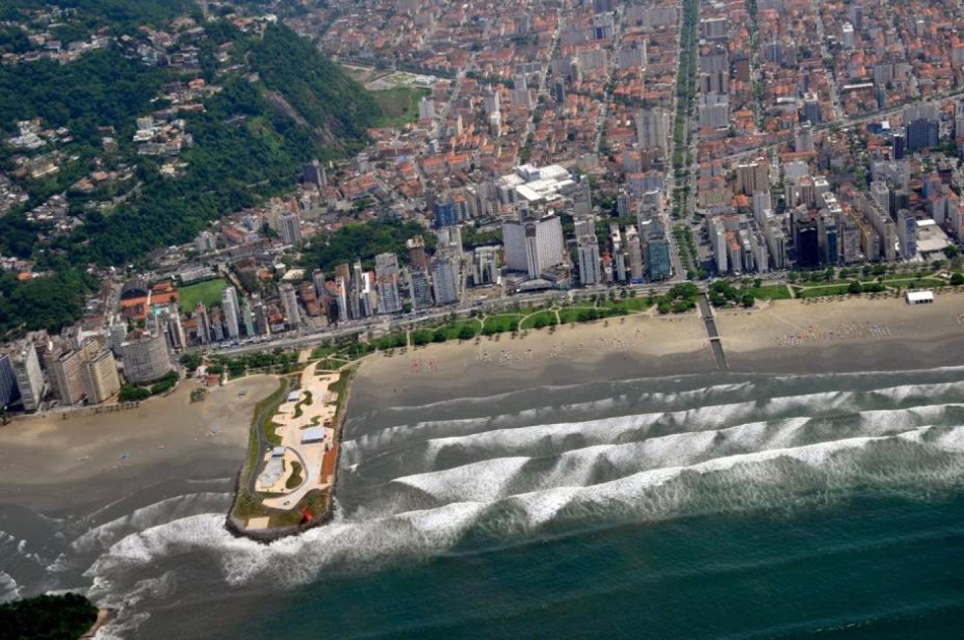Foto área de Santos aparecendo praia, areia, prédios e morro. #paratodosverem