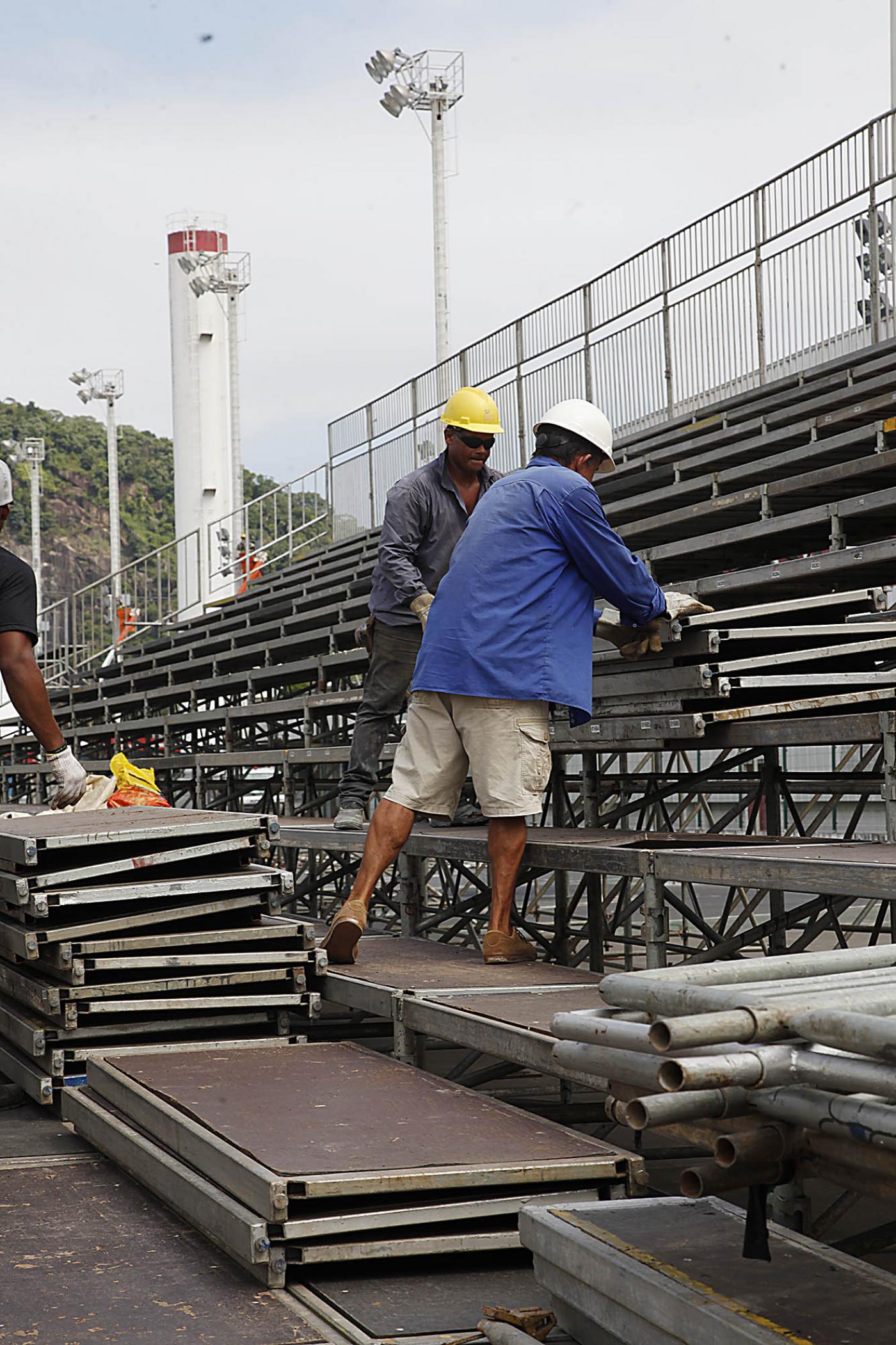 Homens trabalham na montagem de estruturas de ferro. #Pracegover