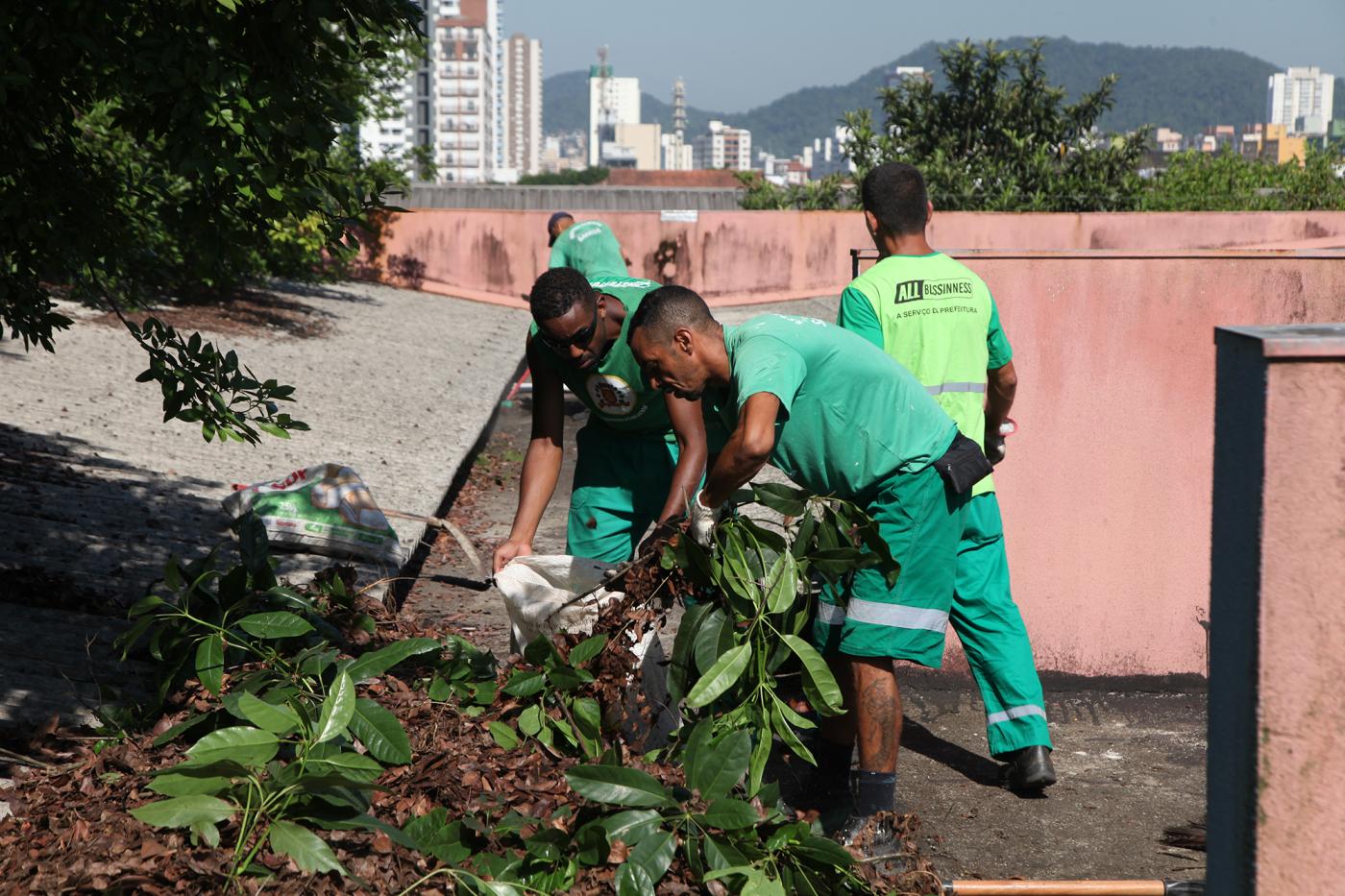 Homens uniformizados retiram folhas de calha. #Paratodosverem