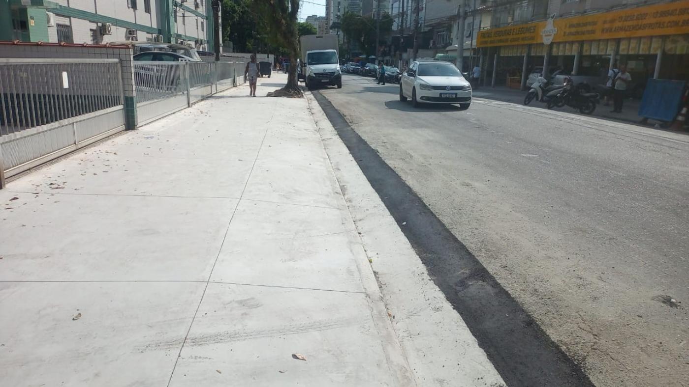 rua com foco em calçada em concreto desempenado novo. Ao lado o leito da rua com um carro passando. #paratodosverem
