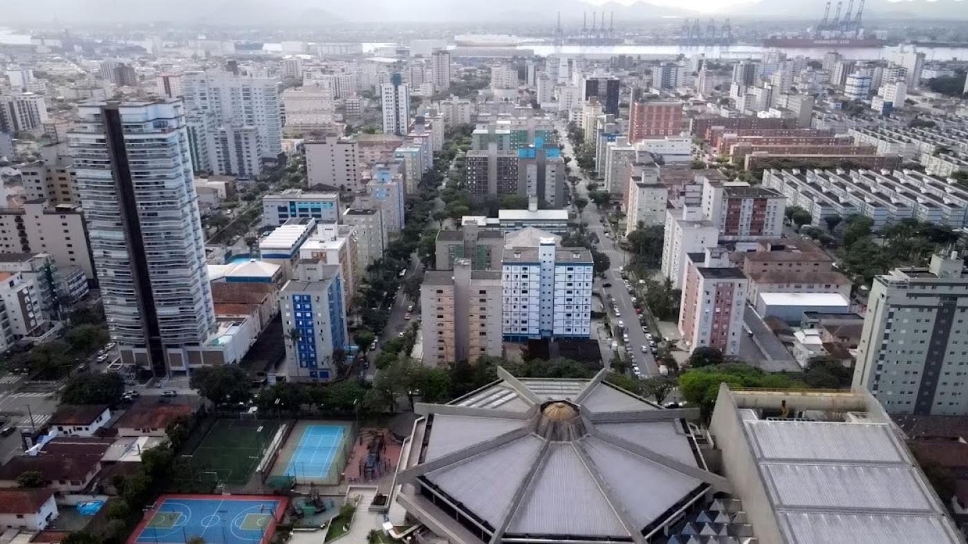 vista geral do bairro, com construções de prédios e casas. Ao longe está o porto. #paratodosverem