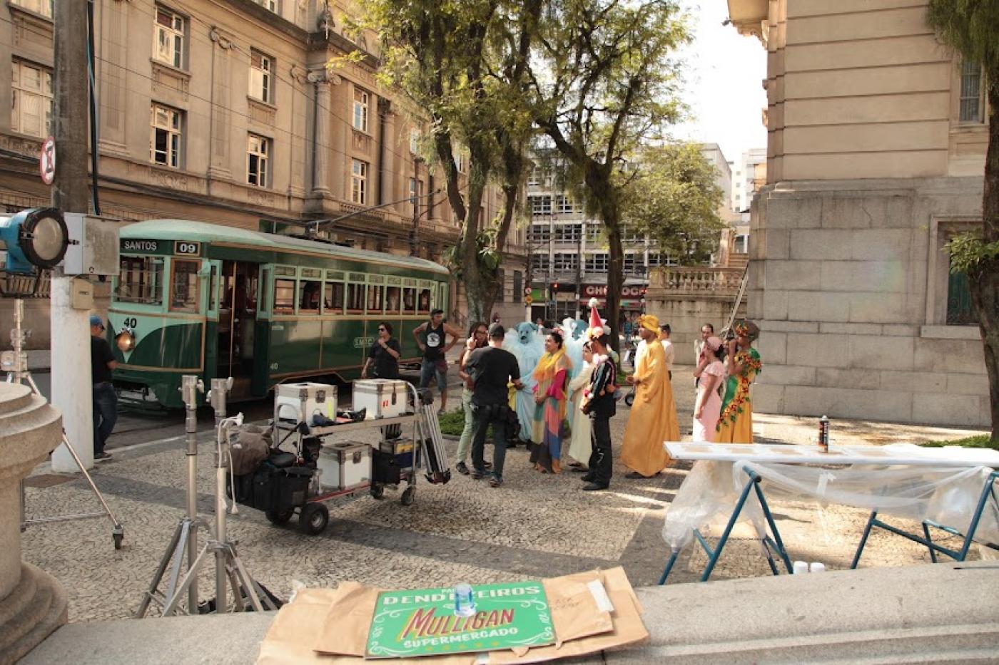 cenário de filmagem montado na praça mauá com bonde ao fundo e pessoas vestidas com roupas de época. #paratodosverem