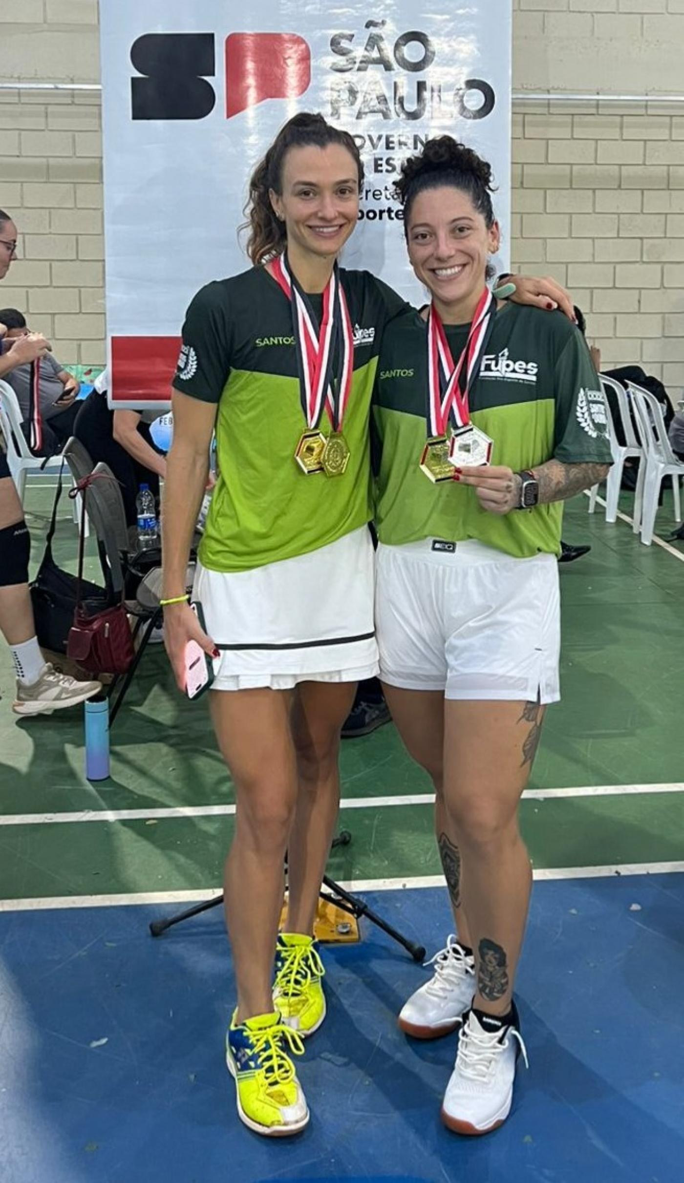Dupla campeã de badminton com medalhas. #Paratodosverem.