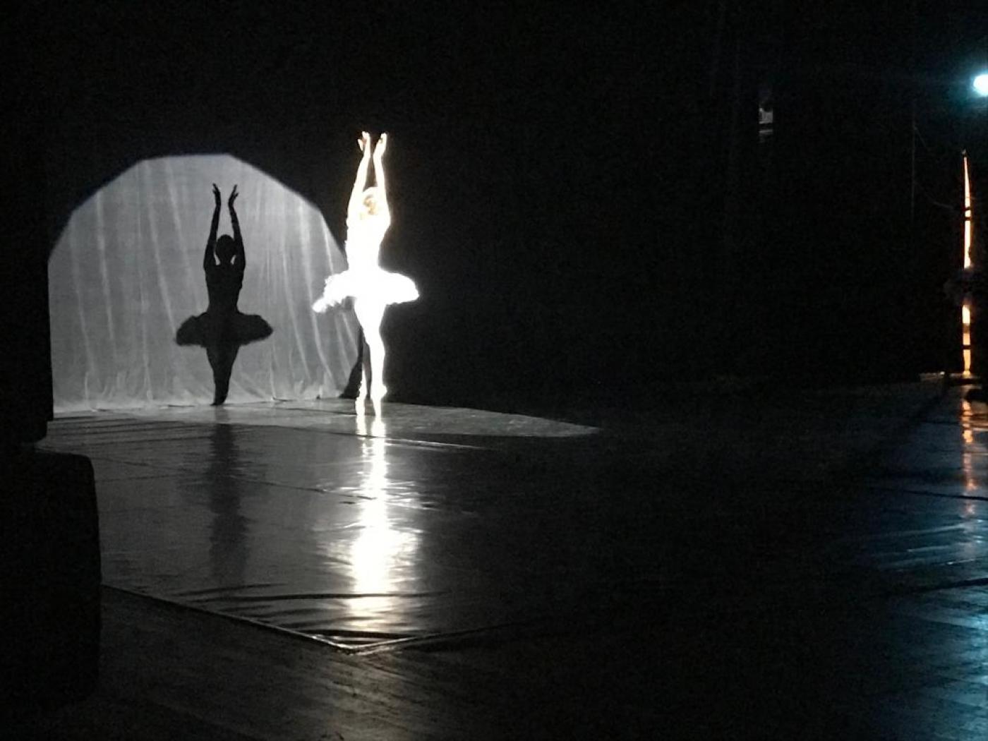 Bailarina faz solo com iluminação focada nela. #pracegover