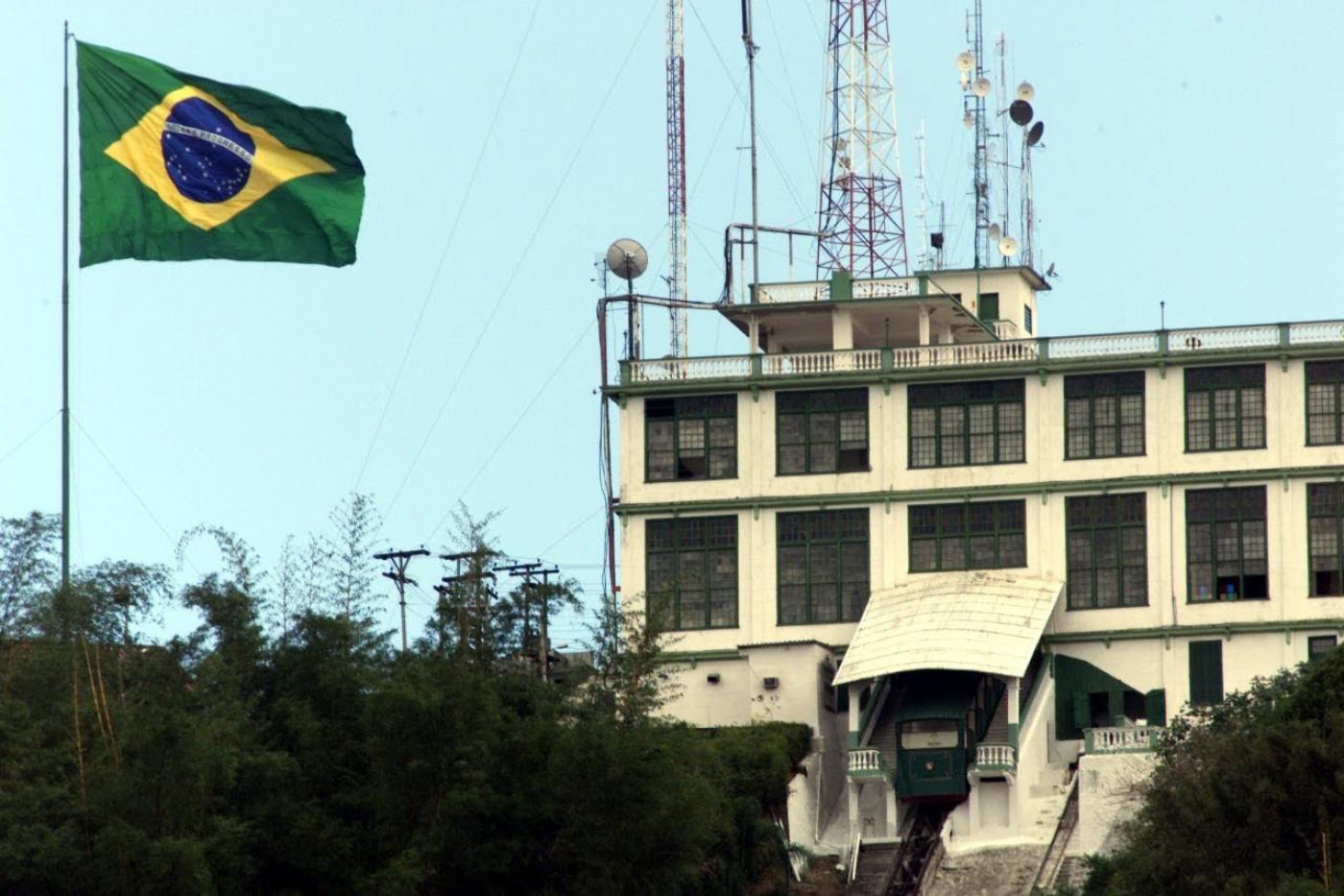 A bandeira do brasil hasteada com o prédio do antigo cassino do Monte Serrat ao lado. #Paratodosverem
