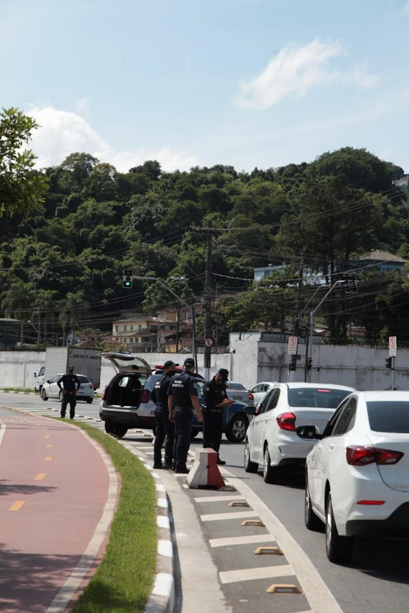 fila de carros na pista que dá acesso à cidade. Guardas e agentes da CET estão próximos ao canteiro central. #Paratodosverem