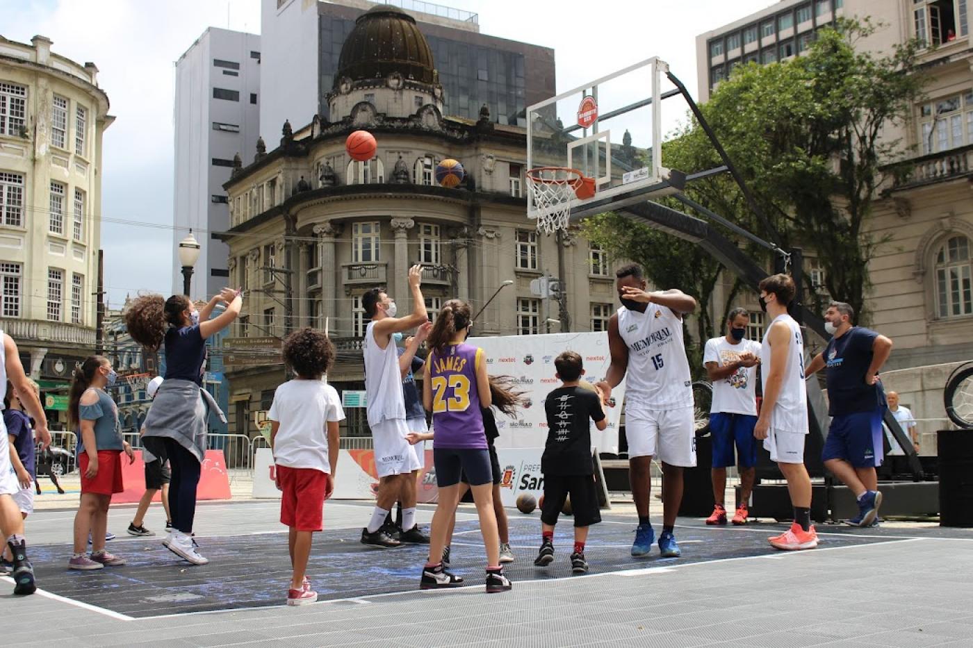 atletas e crianças jogando basquete na praça #paratodosverem