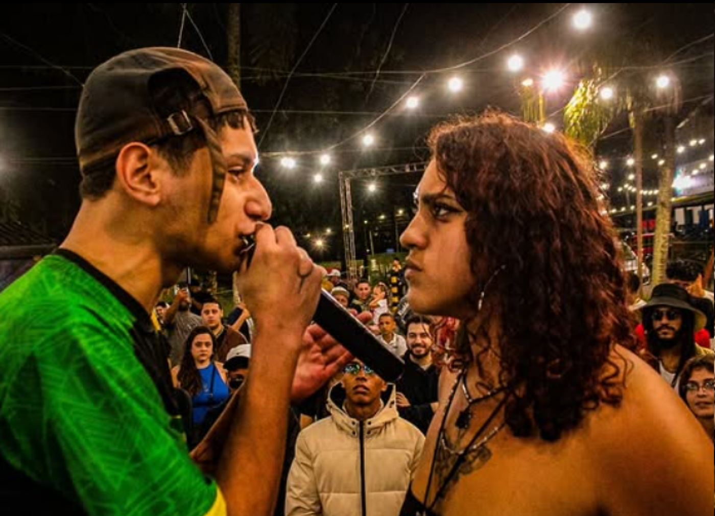 casal se olha enquanto ele canta ao microfone #paratodosverem