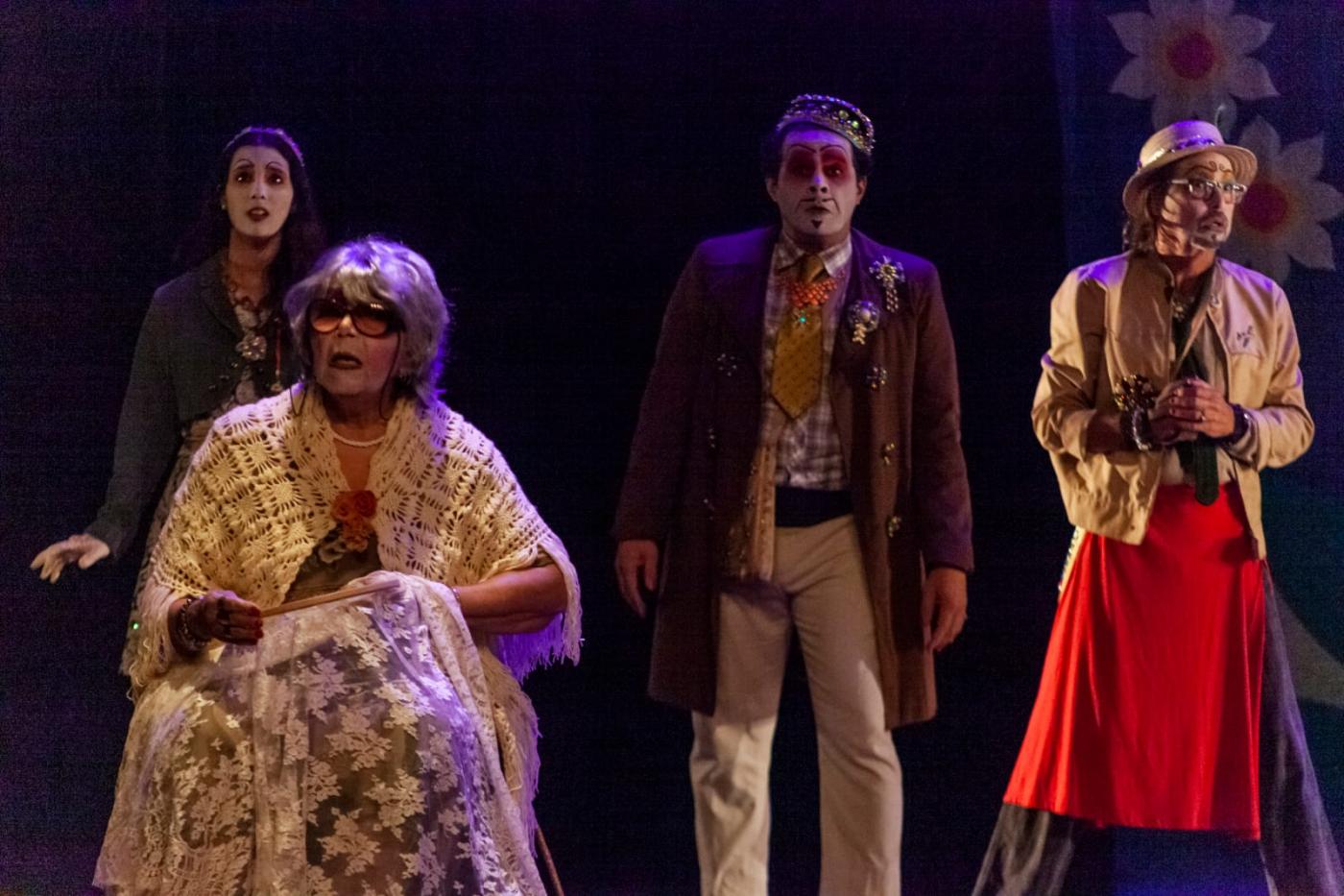 quatro peços em um cenário teatral. Uma delas é uma senhora, que está sentada. Atrás, mais três pessoas. #paratodosverem 