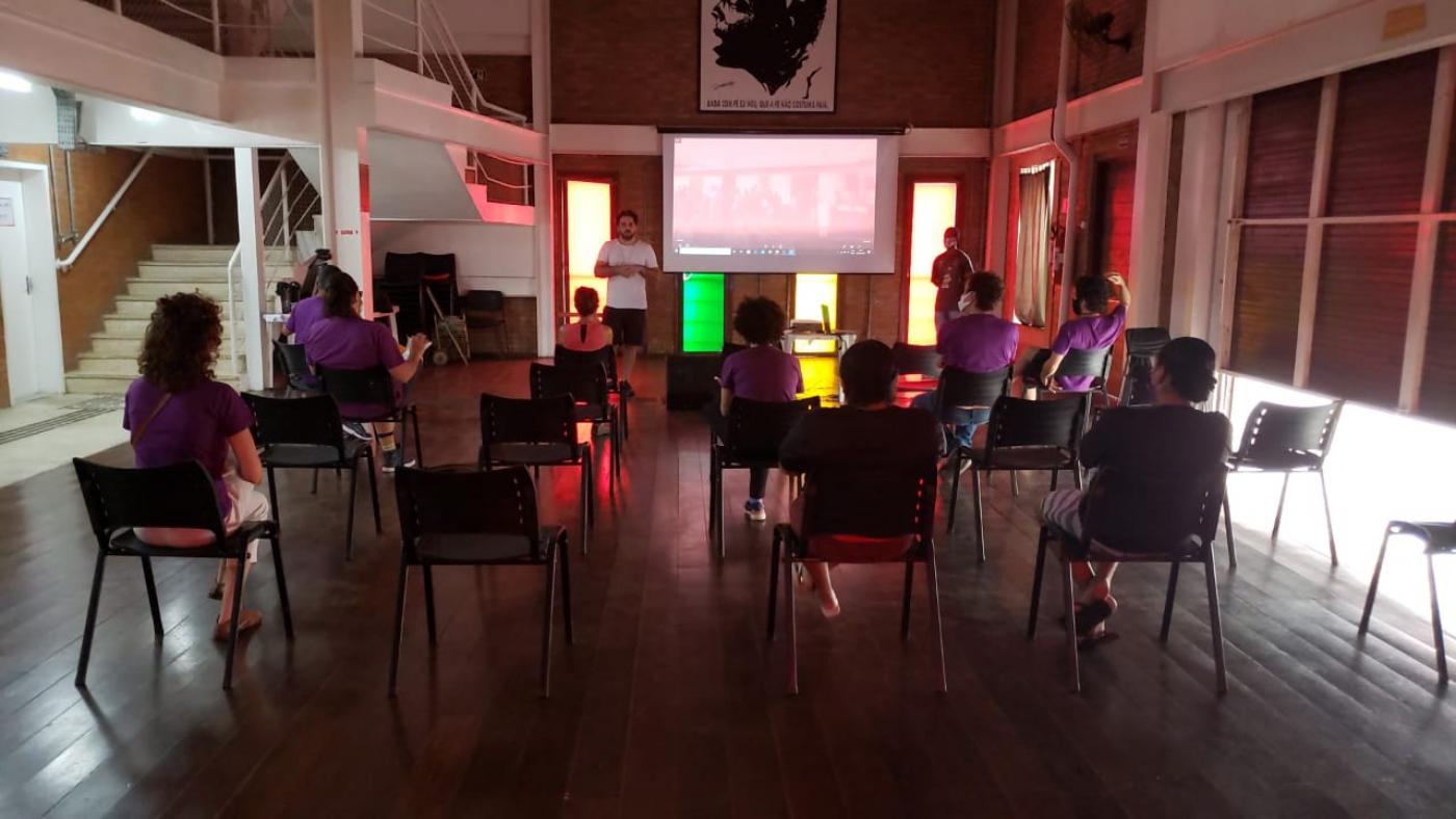 jovens estão em auditório assistindo a projeção. #paratodosverem
