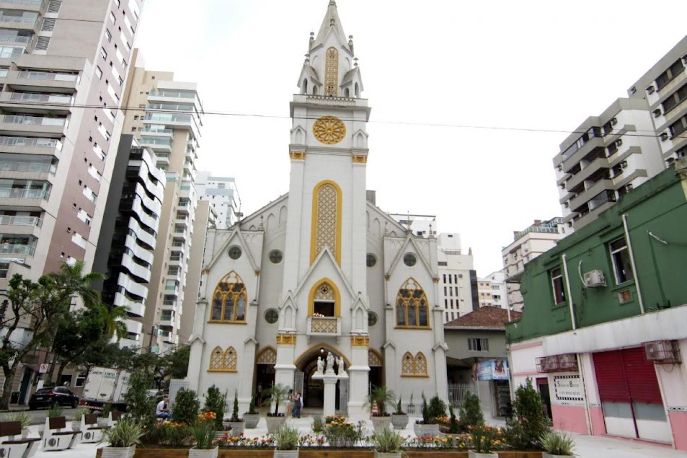 vista geral da praça com a igreja ao fundo. Há prédios nas laterais. #paratodosverem