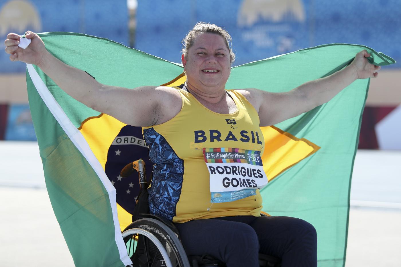 atleta na cadeira de rodas segurando a bandeira do brasil #paratodosverem