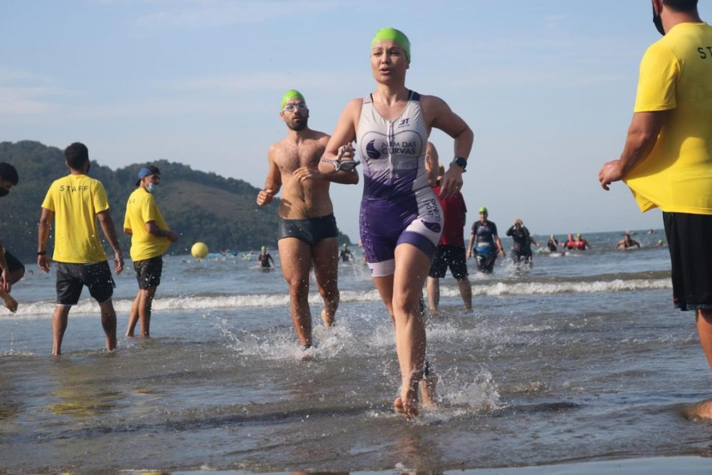 Atletas saem correndo da água após prova de natação. #paratodosverem
