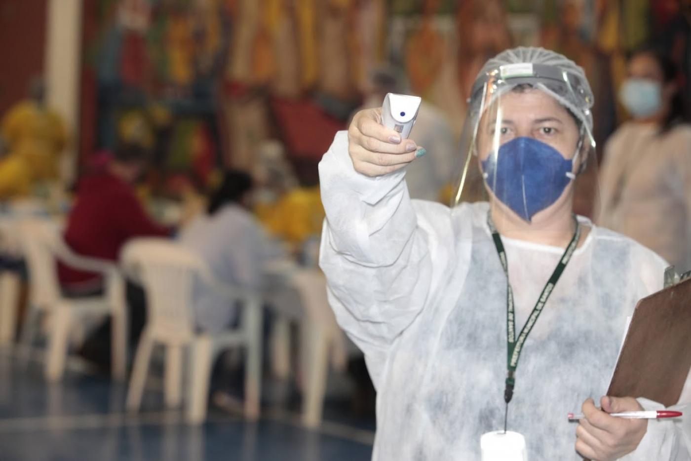 Mulher segura termômetro de testa de frente para a foto. #Paratodosverem