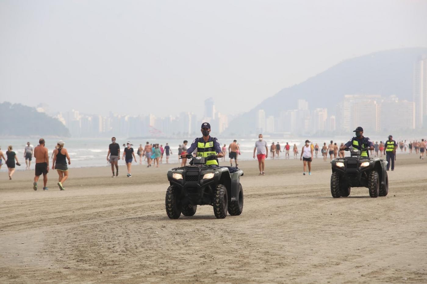 Dois guardas municipais em quadriciclos na faixa de areia. #Paratodosverem