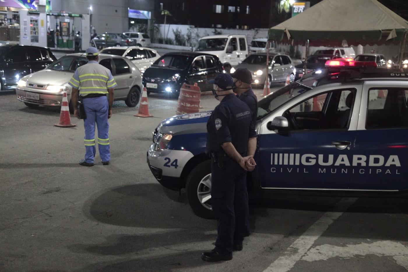 Agente da CET e Guardas municipais estão na pista ao lado de cones. #Paratodosverem