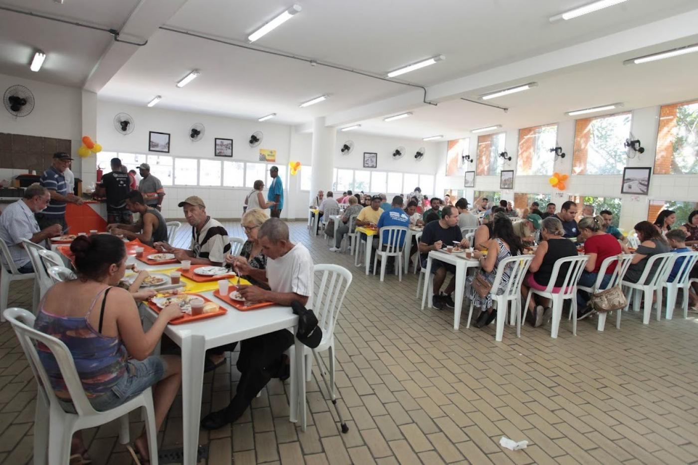 salão de restaurante bom prato com várias pessoas sentadas às mesas e comendo.  #paratodosverem