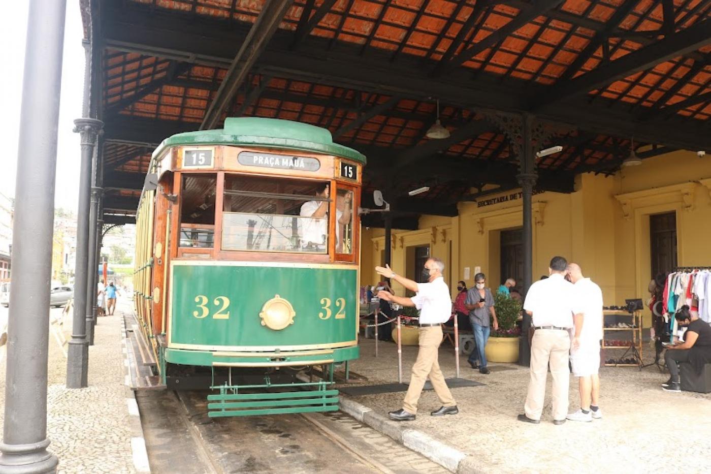 o bonde turístico está parado na estação. Há movimento de pessoas no entorno. #paratodosverem