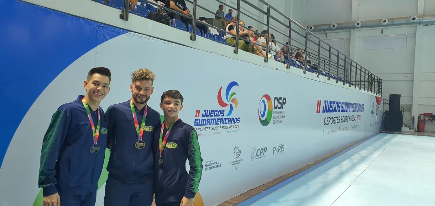 Kevin Medziu, Felipe Werle e Erik Medziu posam para a foto com medalhas no peito. #paratodosverem