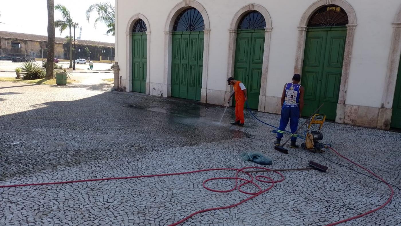 dois homens estão lavando piso de mosaico na frente do museu pelé. Eles usam máquinas e mangueiras. #paratodosverem