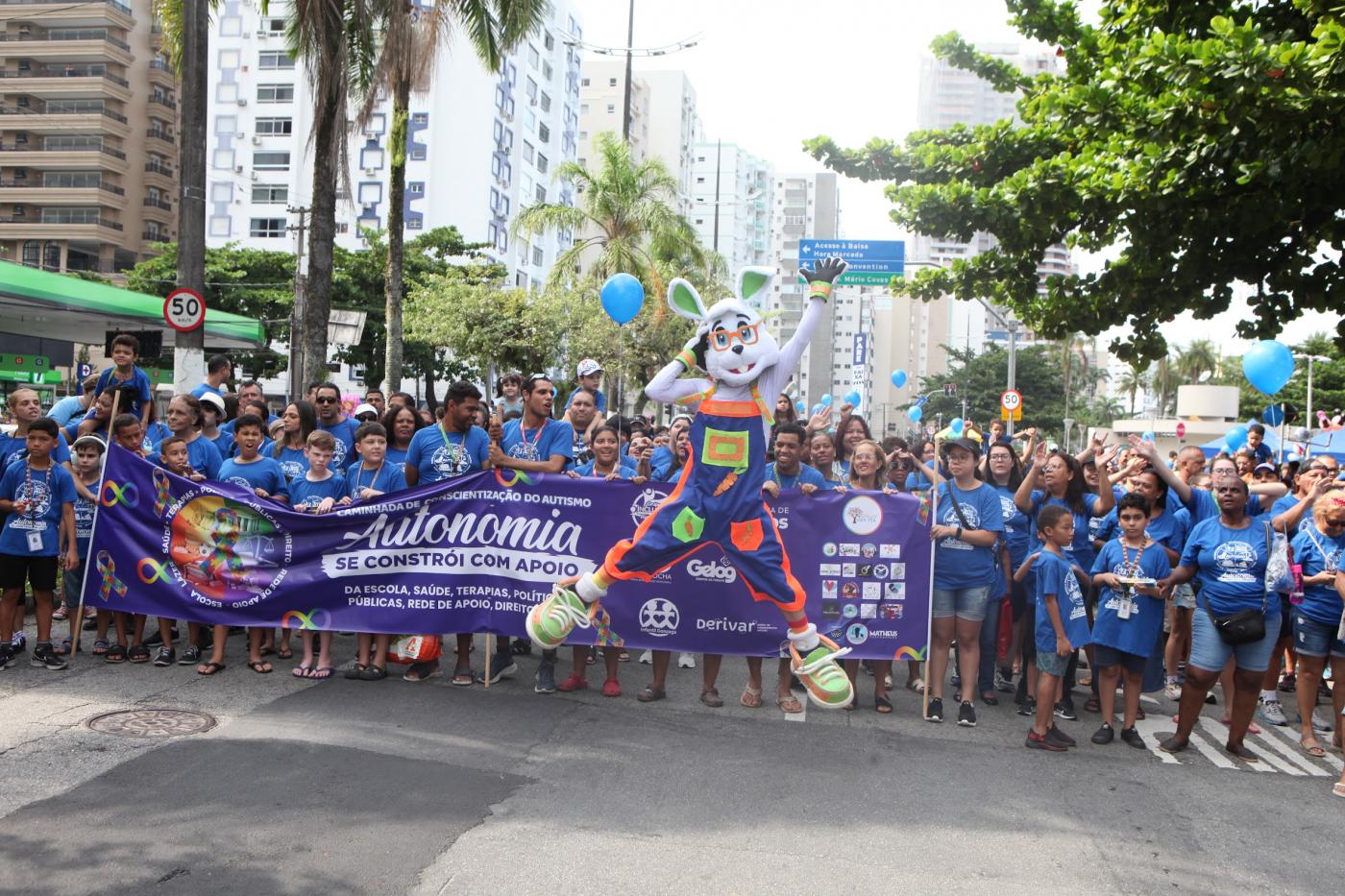 personagem do coelho salta na frente de multidão em caminhada. #paratodosverem