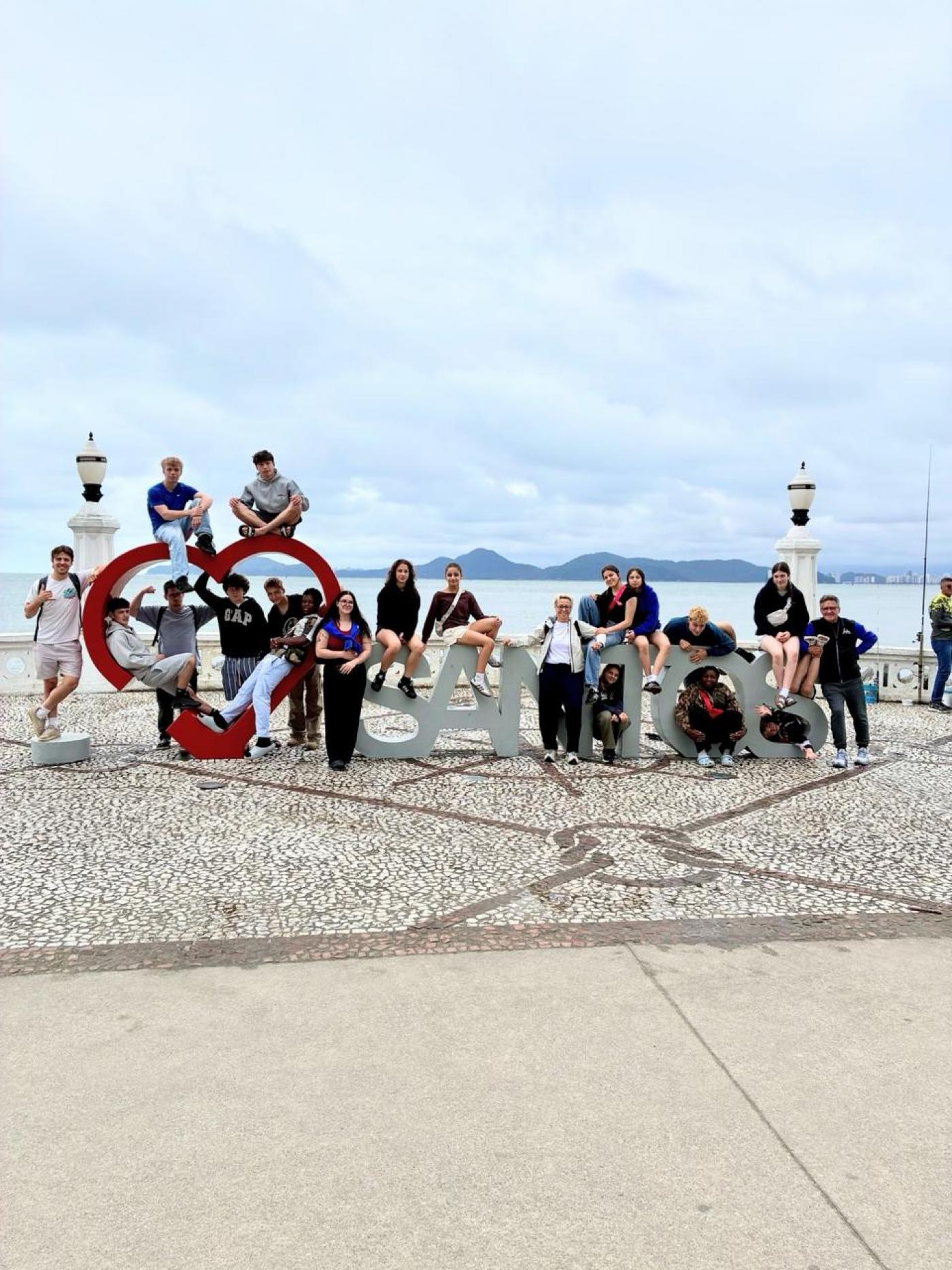 atletas em monumento com o nome da Cidade #paratodosverem