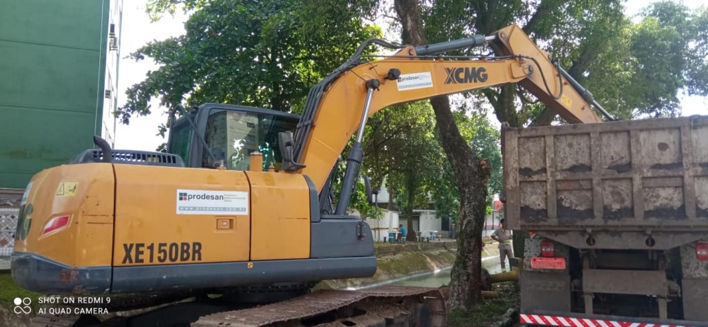 trator com braço basculante que remove detritos de dentro do canal despeja material na caçamba de um caminhão. #paratodosverem