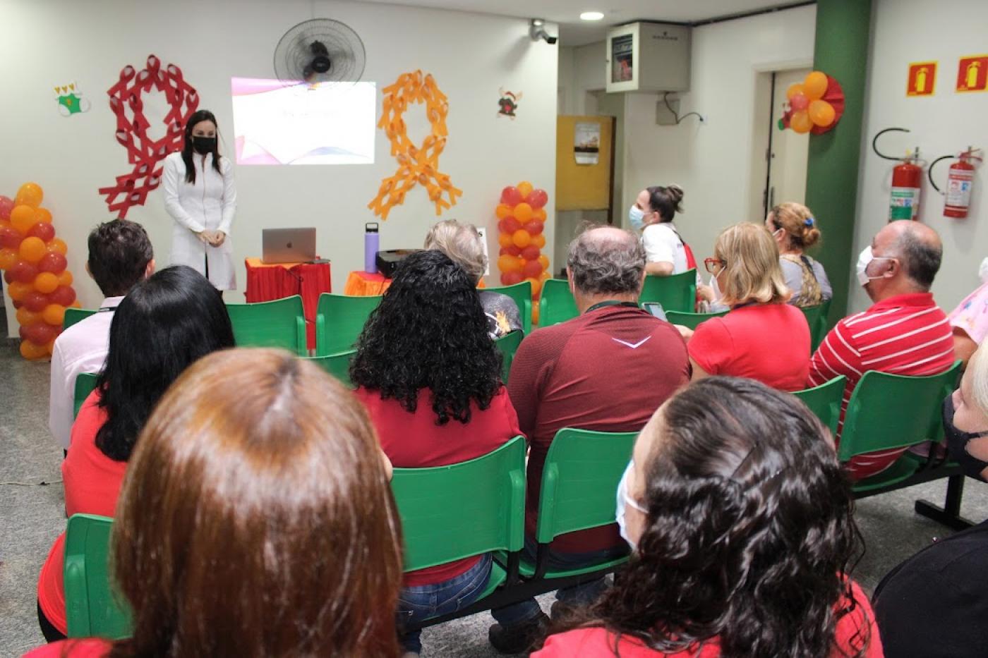 palestrante e várias pessoas sentadas #paratodosverem