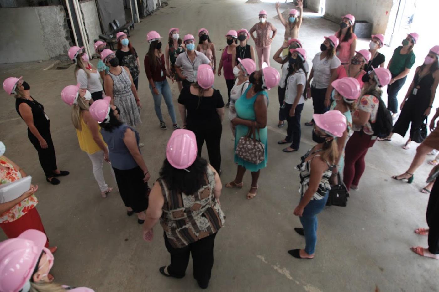 Servidoras com capacetes rosa observam obra em andamento. #pratodosverem