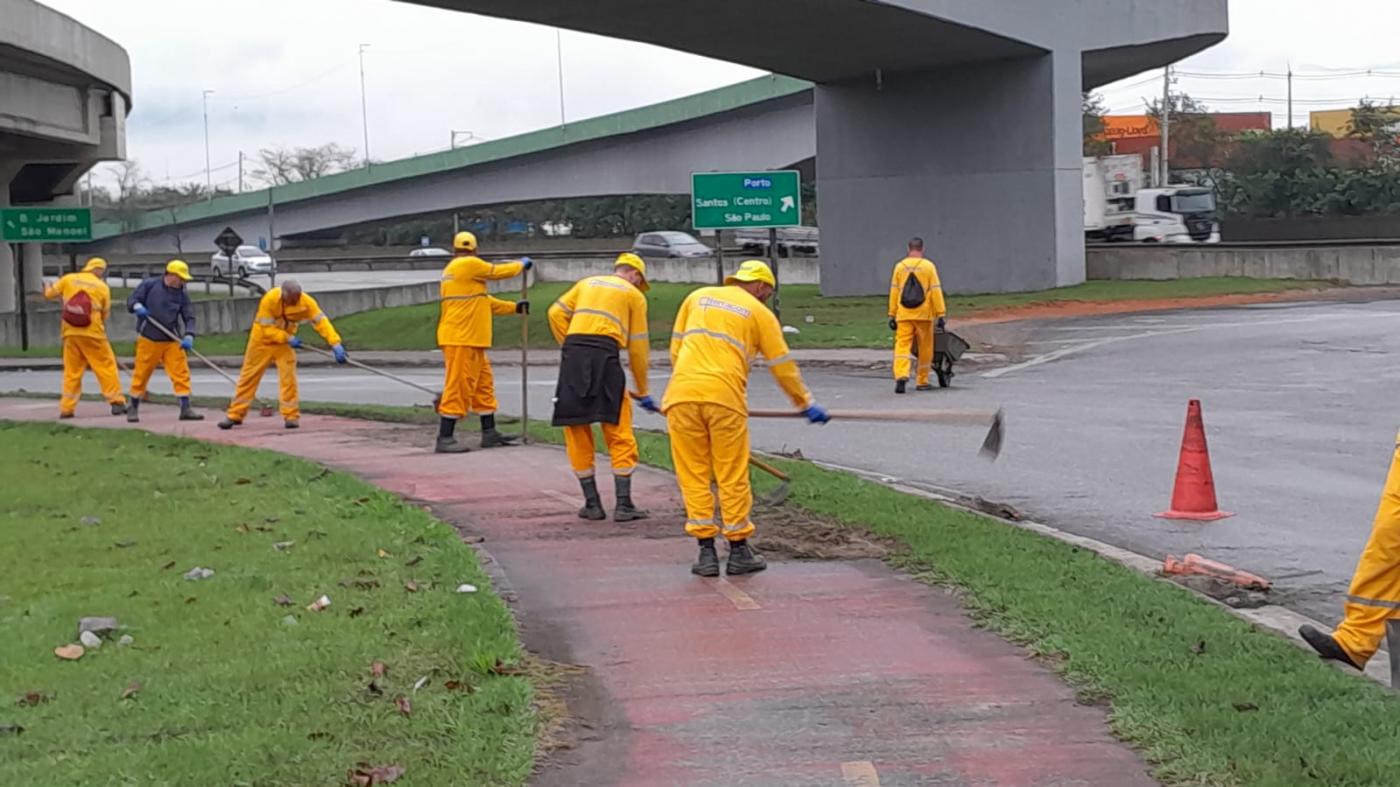 homens uniformizados capinam canteiro em avenida. #paratodosverem 