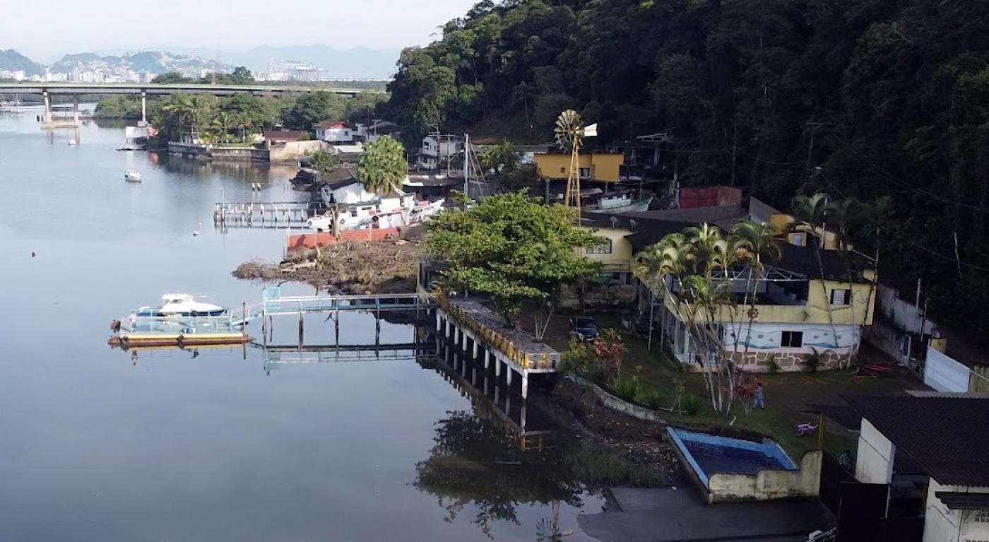 vista aérea do bairro monte cabrão, com o mar do lado esquerdo, pequenas construção em uma faixa entre o morro à direita.#paratodosverem 