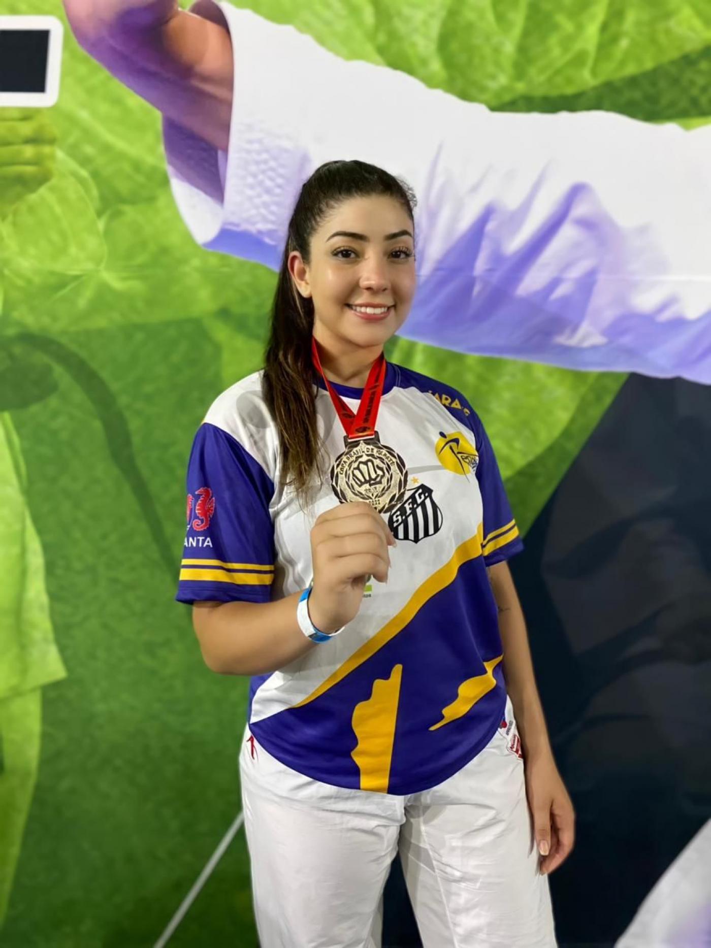 Rafaela Beatriz Silva posa para foto segurando medalha na mão direita. #paratodosverem