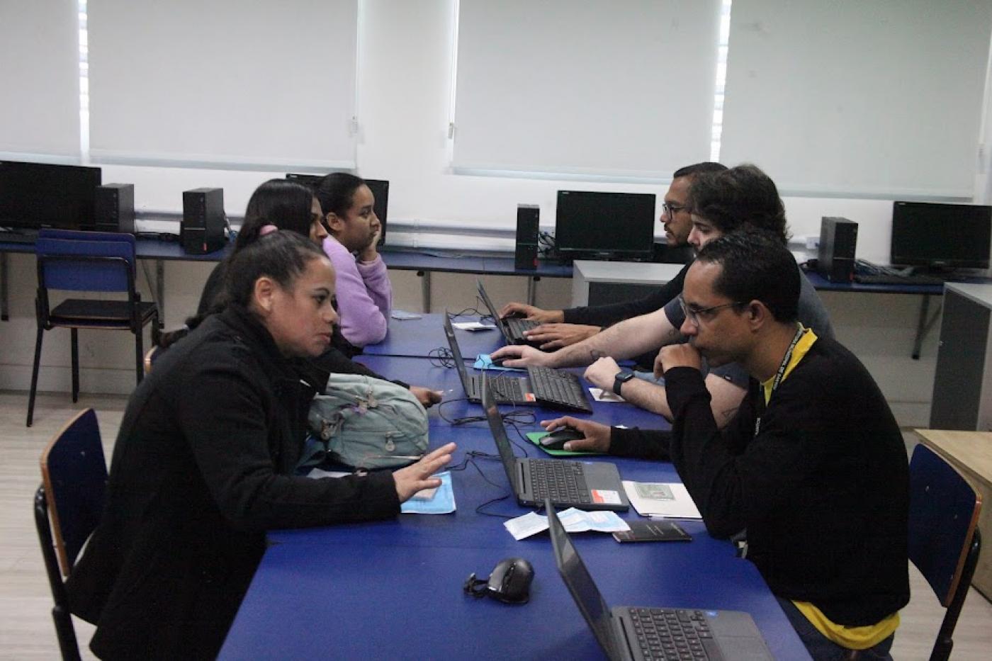 Mulheres conversam com atendentes do Centro Público de Emprego. #pratodosverem