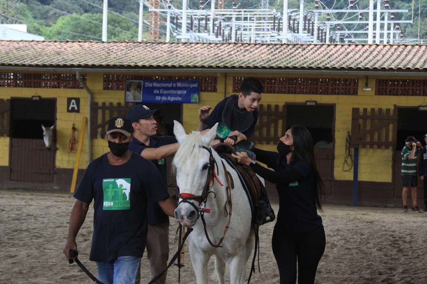 criança em cima do cavalo com pessoas acompanhando #paratodosverem