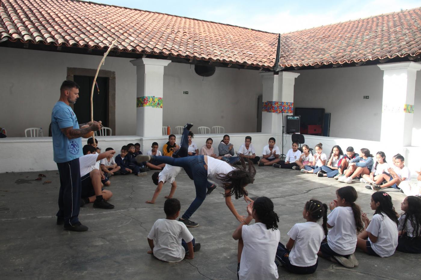 crianças jogam capoeira em quadra. #paratodosverem