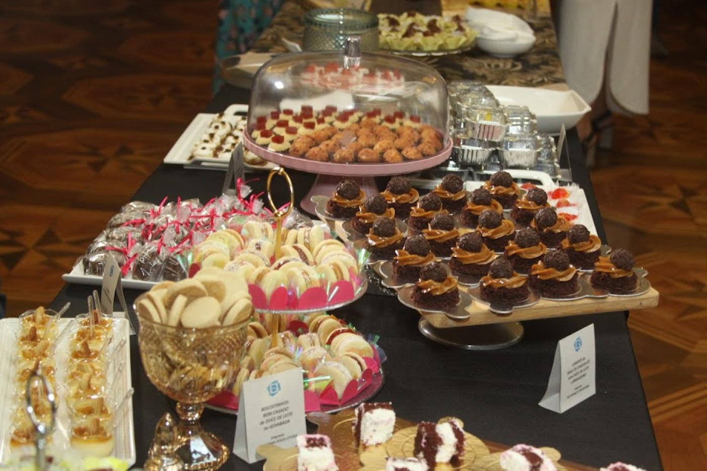 mesa cheia de pratos com doces e salgados expostos. #paratodosverem 