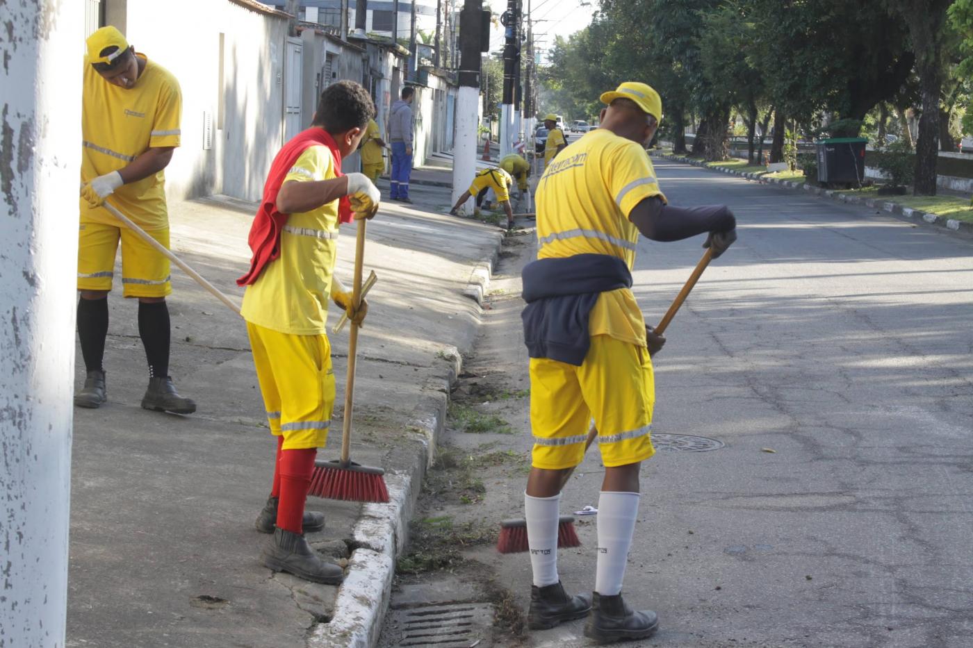 dois homens varrem rua. #paratodosverem