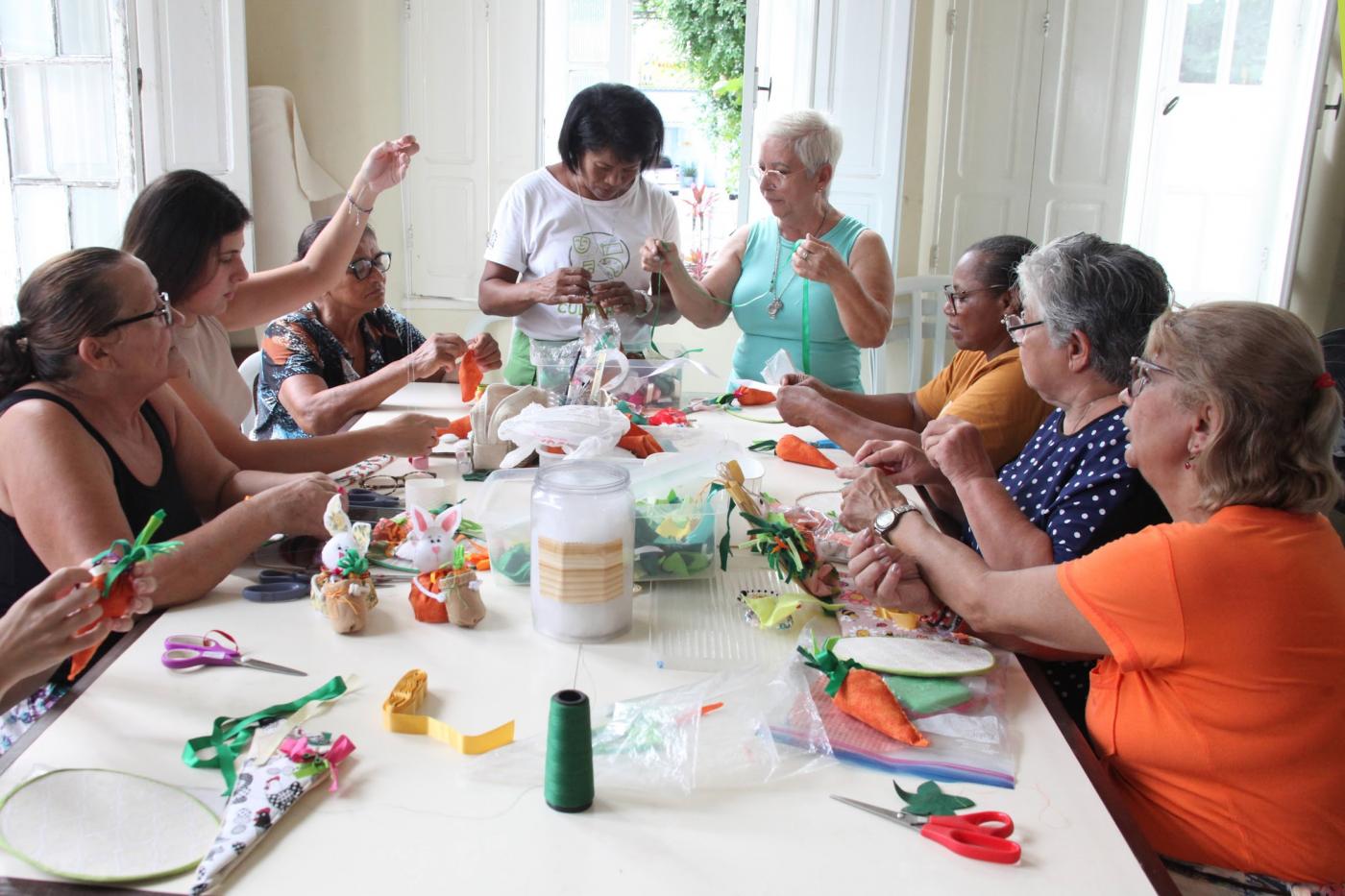 mulheres reunidas fazem artesanato. #paratodosverem 