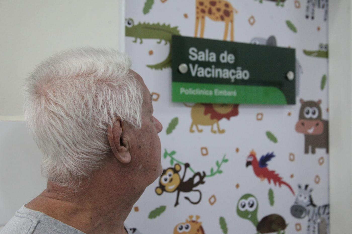 close de idoso diante de sala de vacinação. #paratodosverem