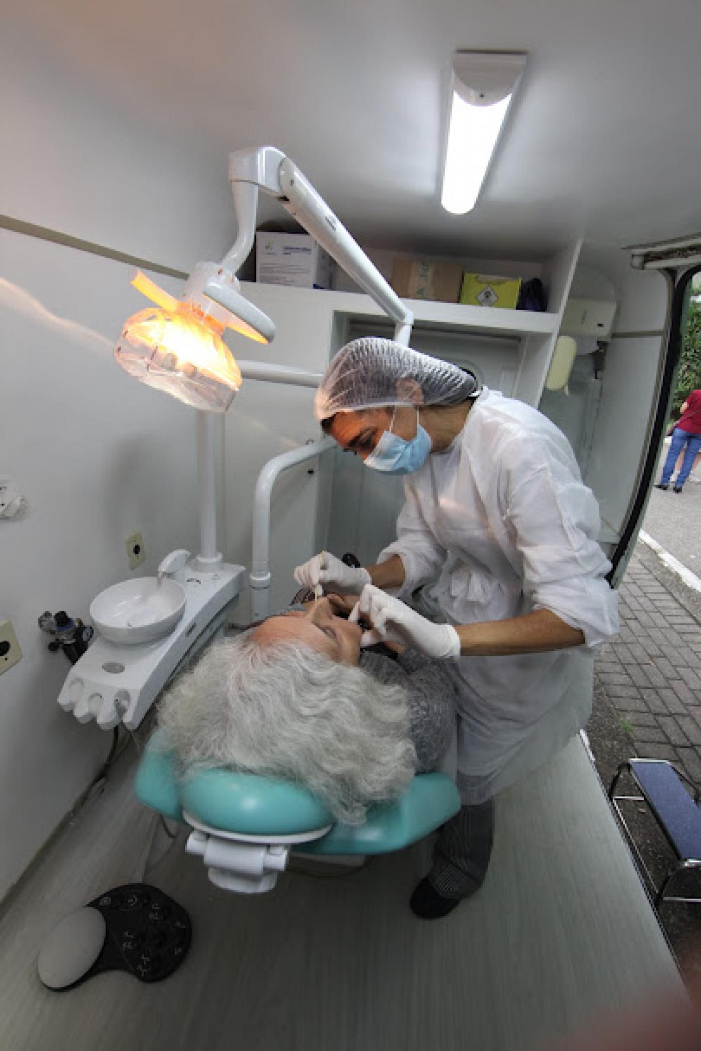 mulher está deitada em cadeira odontologica sendo atendida por uma dentista. #paratodosverem 