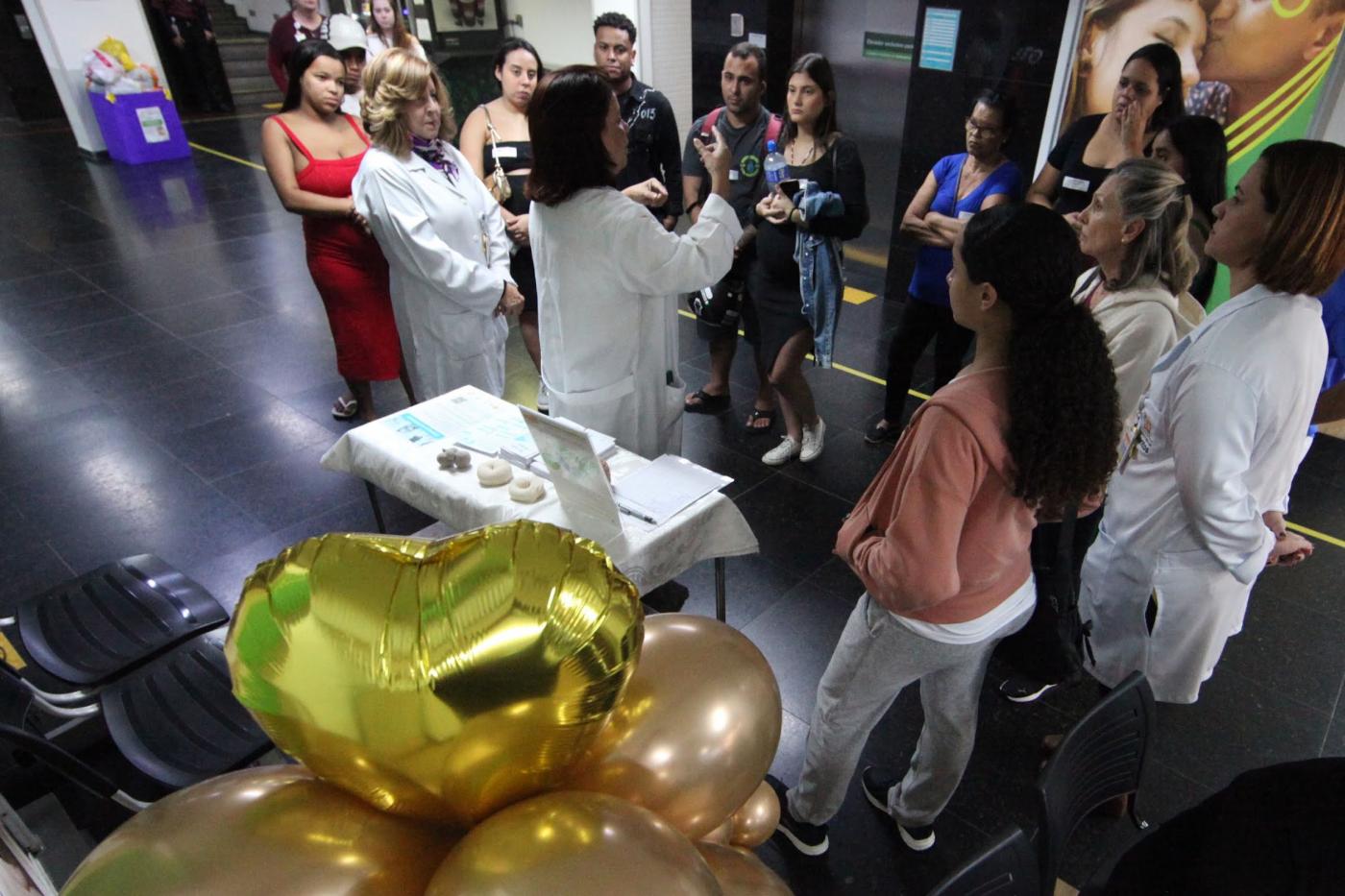 mulheres reunidas em saguão ouvem palestra. #paratodosverem