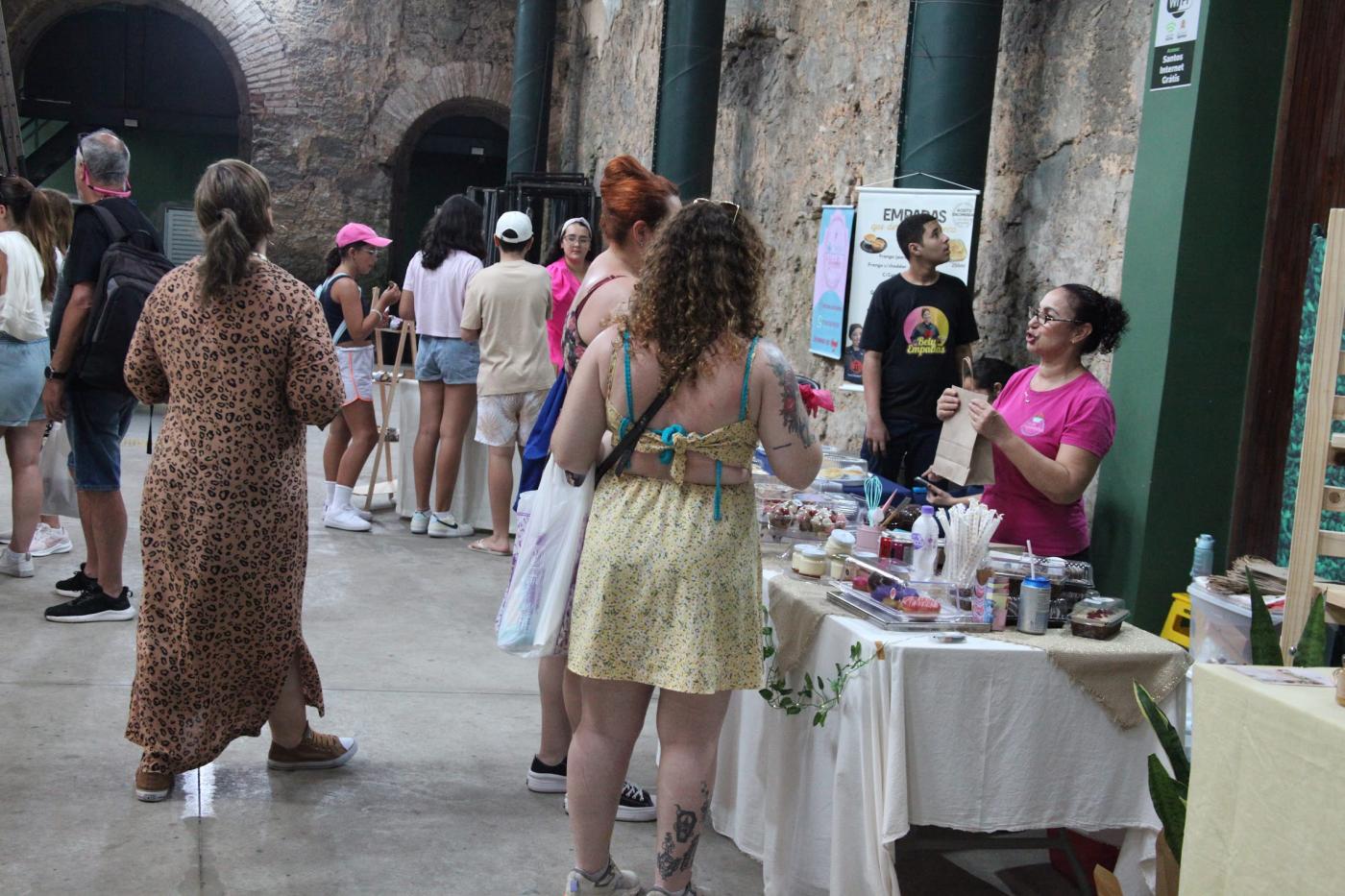 ambiente com exposicão de artesanato e pessoas circulando. #paratodosverem