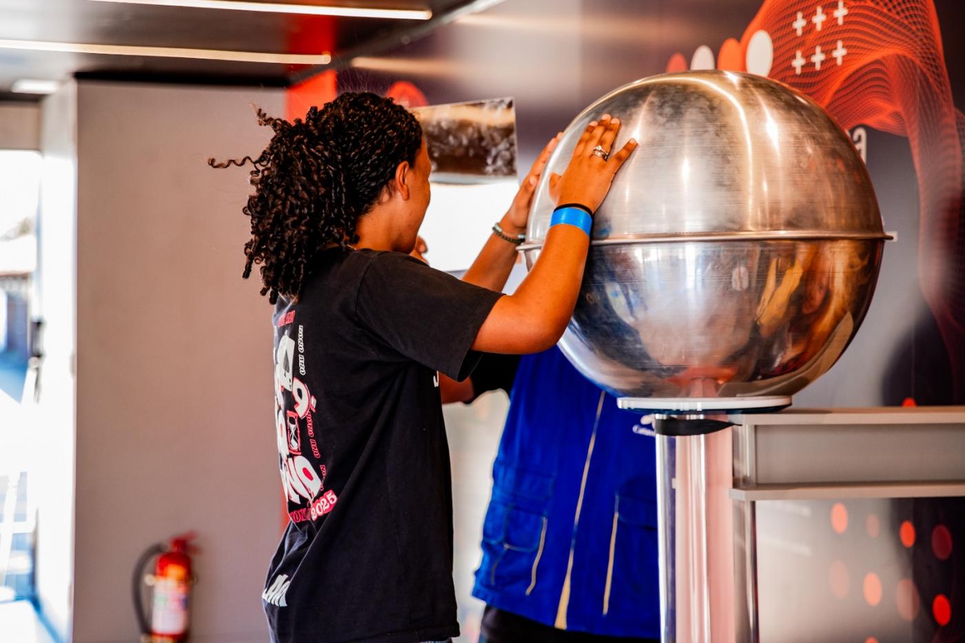 menina encosta em bola prateada #paratodosverem 